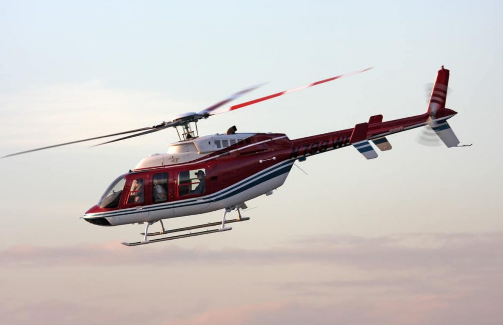 Helicóptero Bell 407 sobrevolando un paisaje impresionante, ofreciendo vuelos panorámicos y transporte aéreo eficiente.